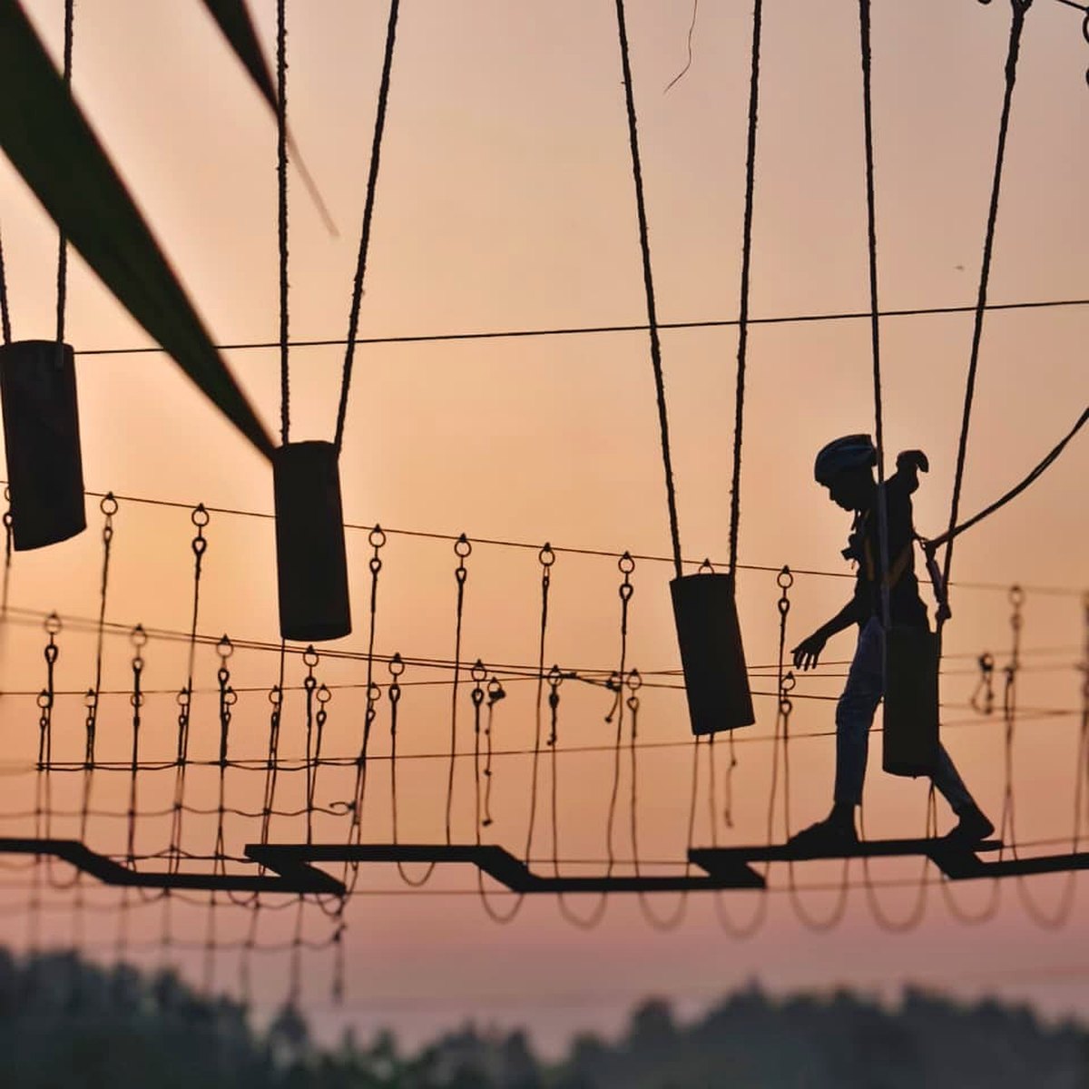 Participant crossing the treetop ropes course at sunset at Tongkaboti Nature Retreat.